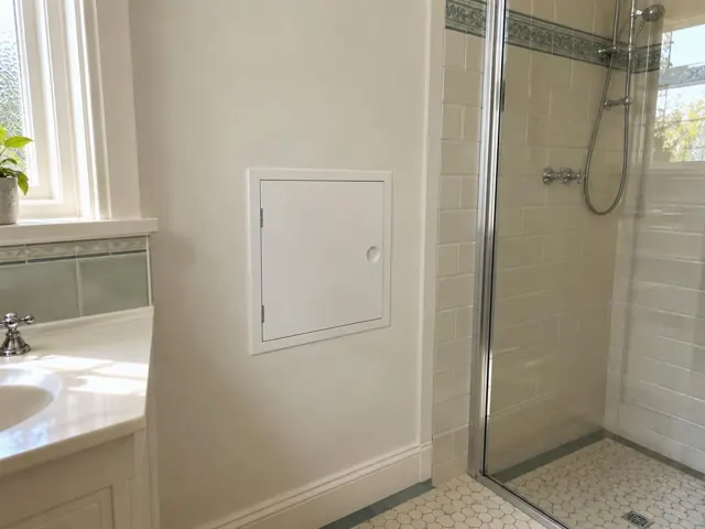 Bathroom wall with a neat access panel beside a shower and vanity in Pelaw Main